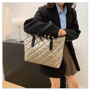 Vue détaillée du sac cabas matelassé or champagne avec anses en cuir noir sur modèle