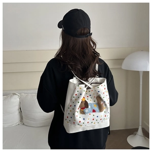 Detail of white backpack with colorful polka dots and cute 3D cartoon dog patch