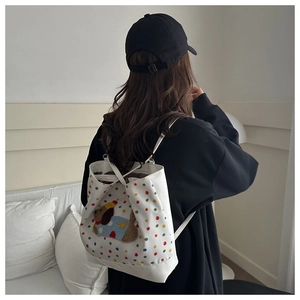 Detail of white canvas drawstring bag featuring colorful polka dots and 3D teddy dog patch