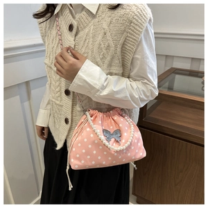 Detail of pink polka dot drawstring bucket bag with silver butterfly clasp and pearl handle