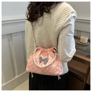 Detailed back view of pink polka dot drawstring bucket bag with pearl handle on model