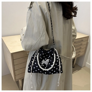 Detailed view of polka dot bucket bag with pearl handle and silver butterfly charm