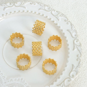 Elegant gold plated honeycomb hollow rings with zircon crystals on a white ceramic plate