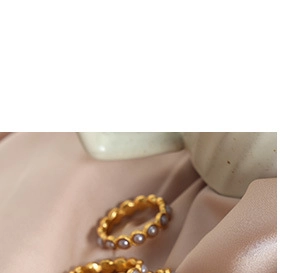 Gros plan de bagues vintage dorées avec perles sur un fond en soie rose élégant