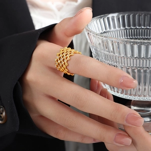 Gold-plated honeycomb ring with sparkling zircons worn by a model holding a glass