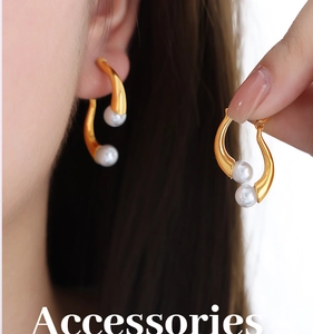 Détail de boucles d'oreilles en perles baroques avec crochets dorés ondulés