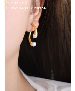 Vue détaillée des boucles d'oreilles asymétriques en perles dorées portées par un mannequin