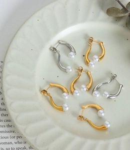 Détail de boucles d'oreilles courbées en C avec perles en finitions or et argent