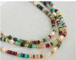 Détail macro de perles en pierre naturelle et perles d'eau douce avec séparateurs dorés texturés