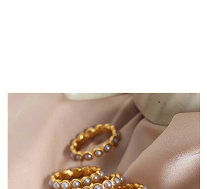 Détail de bagues à vagues plaquées or avec perles d'eau douce sur du tissu en soie