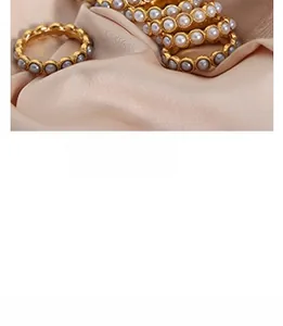 Détail de bagues élégantes plaquées or avec perles sur un tissu en soie rose doux