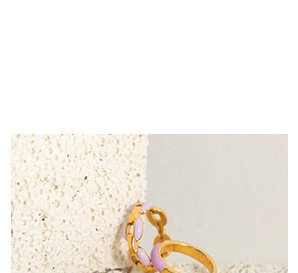 Detail of minimalist gold-plated rings with purple enamel on a white textured stone
