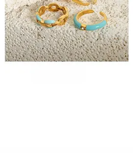 Macro detail of gold-plated chain rings with sky blue enamel and a tiny crystal accent