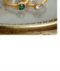 Macro shot of gold-plated rings with vintage texture and emerald green gemstone inlay