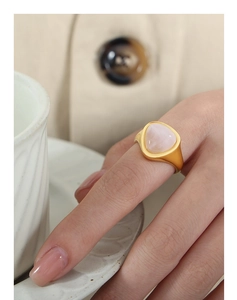 Close-up of a gold-plated stainless steel ring with a soft pink gemstone worn on finger