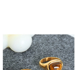 Gros plan sur bague triangulaire dorée ornée d'une pierre œil de tigre marron