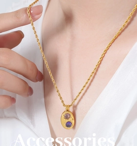 Détail du collier à chaîne torsadée dorée avec pendentif ovale étoilé et pierres mauves