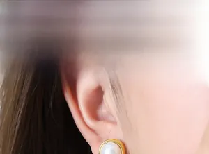 Detail of round pearl stud earrings with gold metal frame showing elegant luster