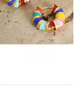 Détail de boucles d'oreilles dorées avec spirale et incrustation d'émail multicolore