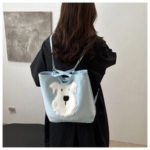 Detail of light blue tote bag featuring a white plush Schnauzer dog motif and shoulder straps