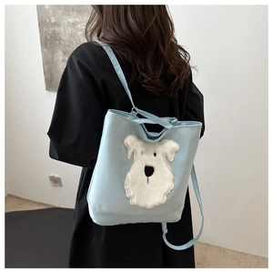 Close-up of light blue canvas tote bag with a white plush dog patch on long black coat