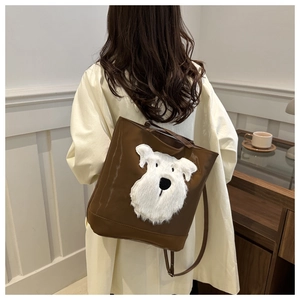 Detail view of brown casual backpack featuring fluffy white dog plush patch for daily use.
