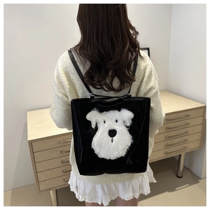 Detail shot of black patent leather tote backpack featuring a cute fluffy white puppy design.