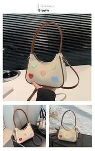Dettaglio borsa hobo beige con toppe a cuore colorate e finiture in pelle marrone chic