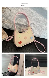 Dettaglio della borsa intrecciata con toppe a cuore colorate e tracolla rosa