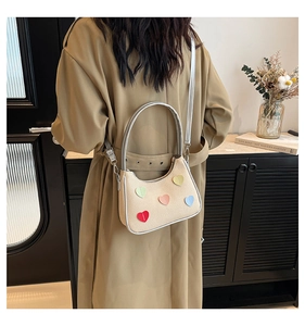 Modella che indossa borsa hobo in tela beige con cuori colorati e manico argento