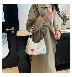 Dettaglio borsa a mano beige testurizzata con toppe a cuore colorate e manico