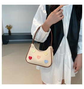 Dettaglio della borsa hobo in tela beige con cinque patch a cuore e finiture in cuoio