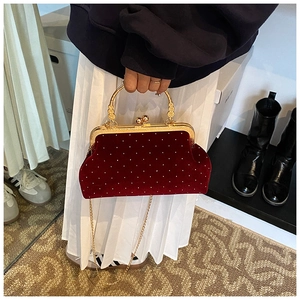 Close-up of red velvet evening bag with white polka dots and ornate gold handle