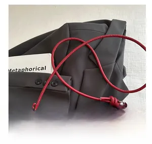 Detail of red leather shoulder bag featuring knotted strap and elegant silver metal ring