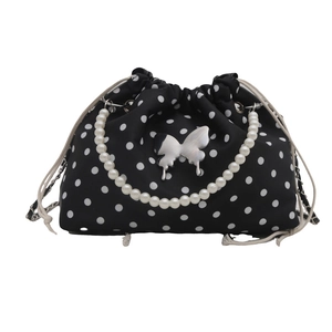 Elegant black bucket bag with white polka dots and pearl handle shown on white background