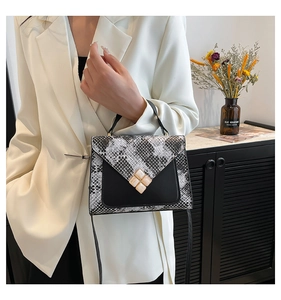 Detail van de slangenprint en de juwelensluiting op deze luxe handtas