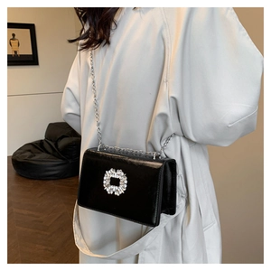 Detail of black crossbody bag with silver chain and oversized sparkling rhinestone buckle