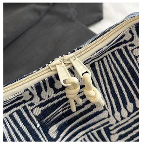 Detail of high-quality YKK zipper on a woven striped tote bag with smooth texture