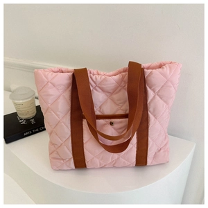Detail of pink quilted tote bag showing rhombus stitching and brown nylon straps