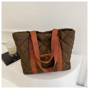 Close-up of quilted nylon tote with brown rhombic stitching and vibrant orange strap