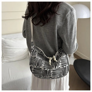 Black and white geometric canvas hobo bag shown on model in a minimalist home setting