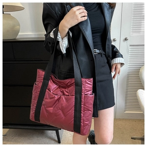 Detail of quilted burgundy tote bag featuring metallic nylon fabric and black shoulder straps