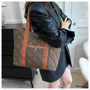 Detailed quilted tote bag in dark brown with orange webbing handles and a metal snap pocket