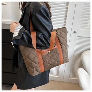 Close-up of brown quilted tote bag with bright orange shoulder strap detail