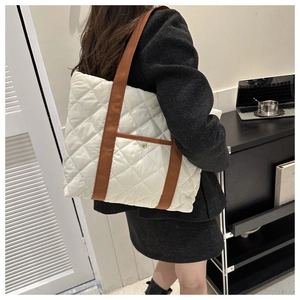 Quilted nylon tote bag detail with brown webbing straps and golden snap button pocket