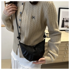 Detail of black crescent dumpling bag showing pleated texture and shoulder knot style