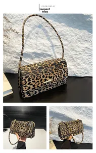 Detail of trendy leopard print baguette bag with golden metal buckle and chain strap