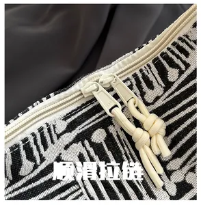 Detail of high-quality dual YKK zippers on a striped tote bag with rope puller detail