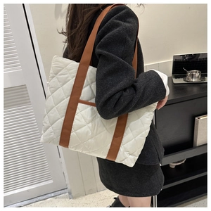 Detail view of cream quilted tote bag with brown straps and large capacity for commuting
