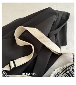Detail of adjustable woven shoulder strap and zipper closure on a black hobo bag
